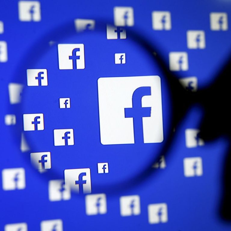A man poses with a magnifier in front of a Facebook logo on display in this illustration taken in Sarajevo
