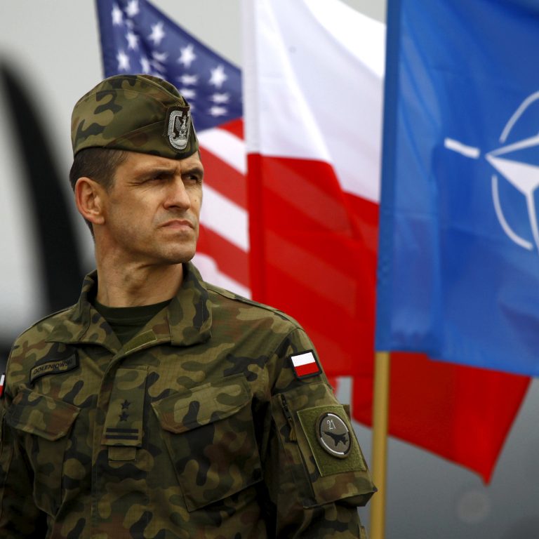 File photo of Polish soldier standing near flags of the U.S, Poland and NATO in Swidwin